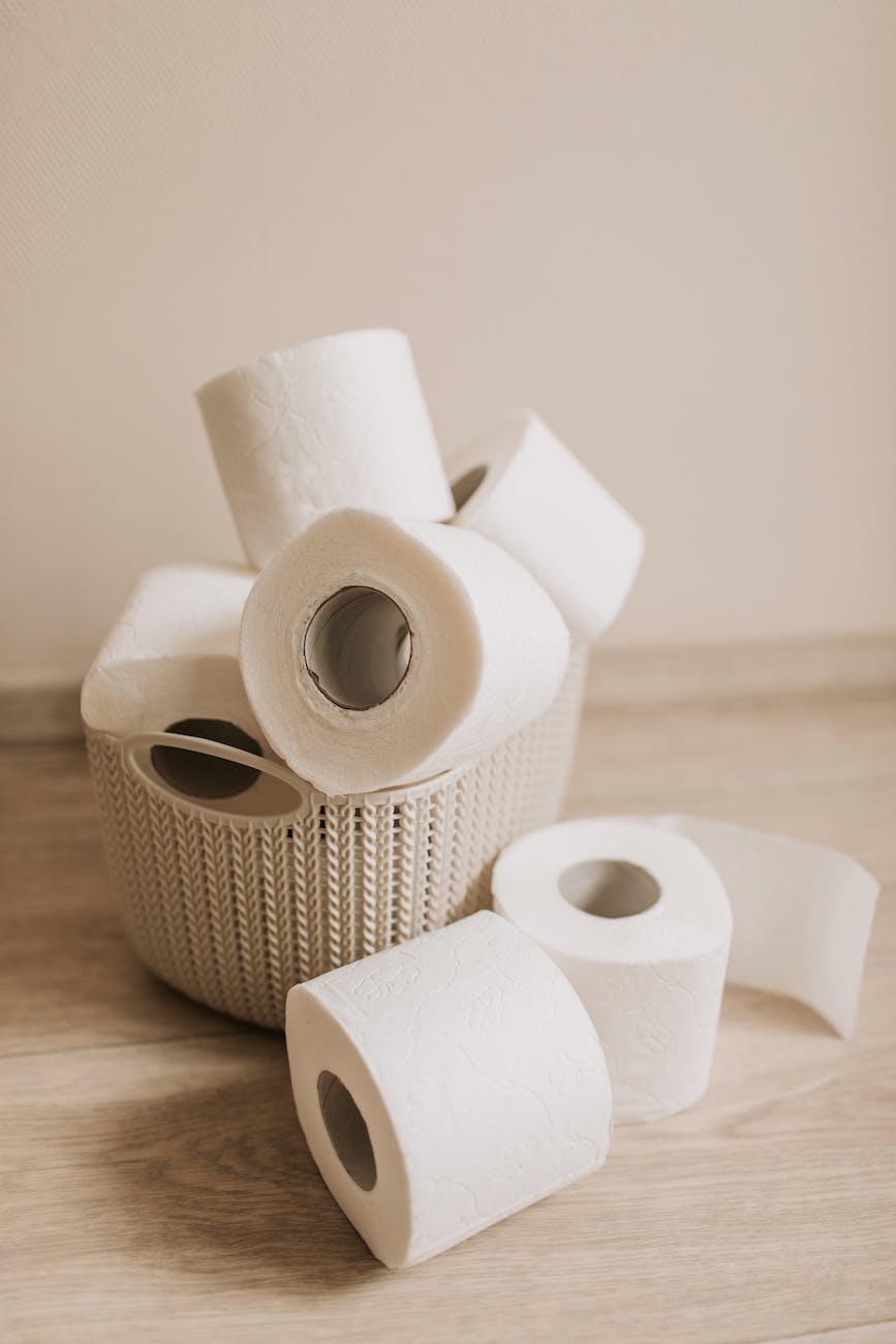 tubes of white toilet paper and plastic basket on bathroom floor